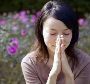 japanese girl praying with flowers in the background
