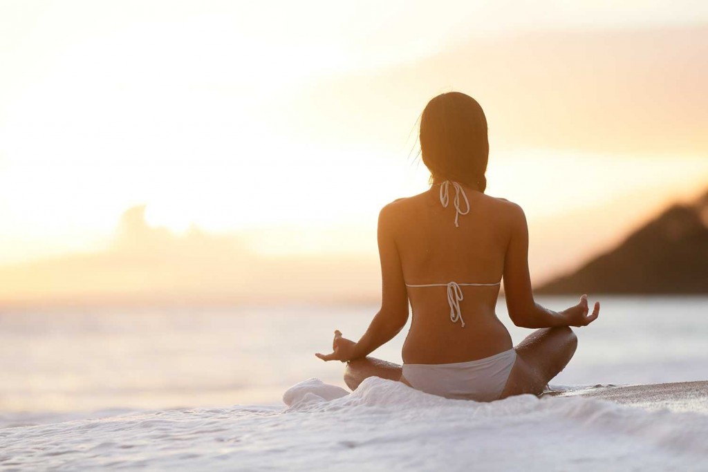 woman in bikini meditating on beach